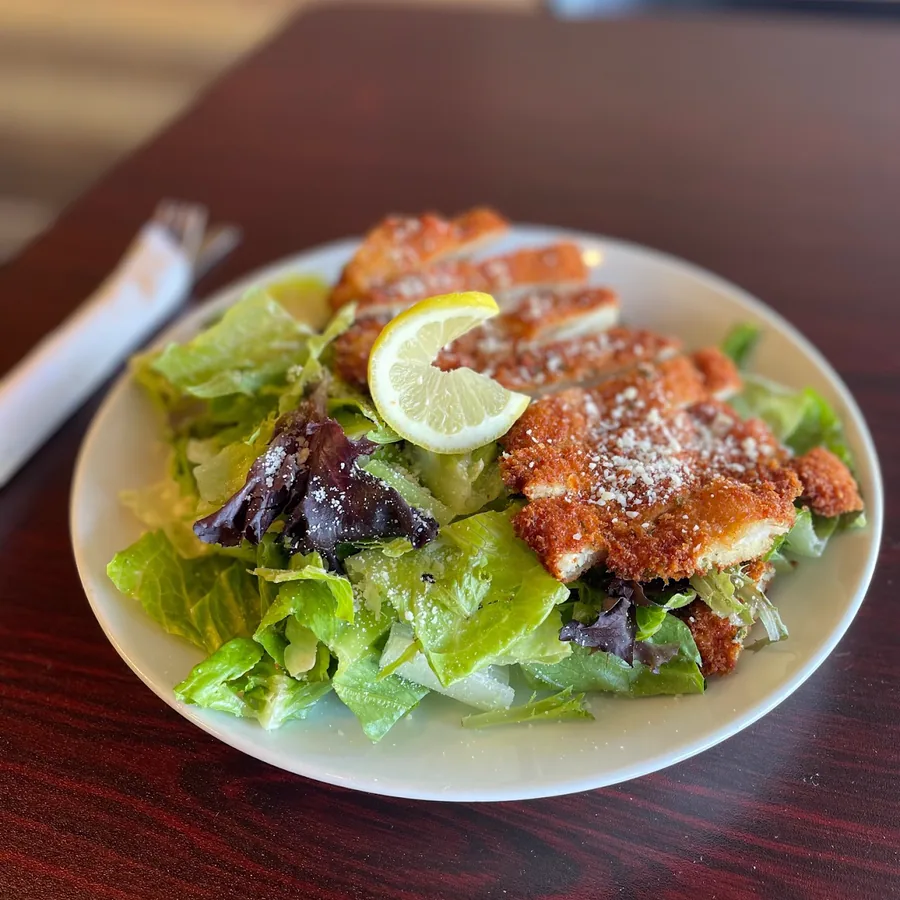 A chicken cutlet salad — crispy breaded chicken sliced over mixed greens with parmesan and lemon.