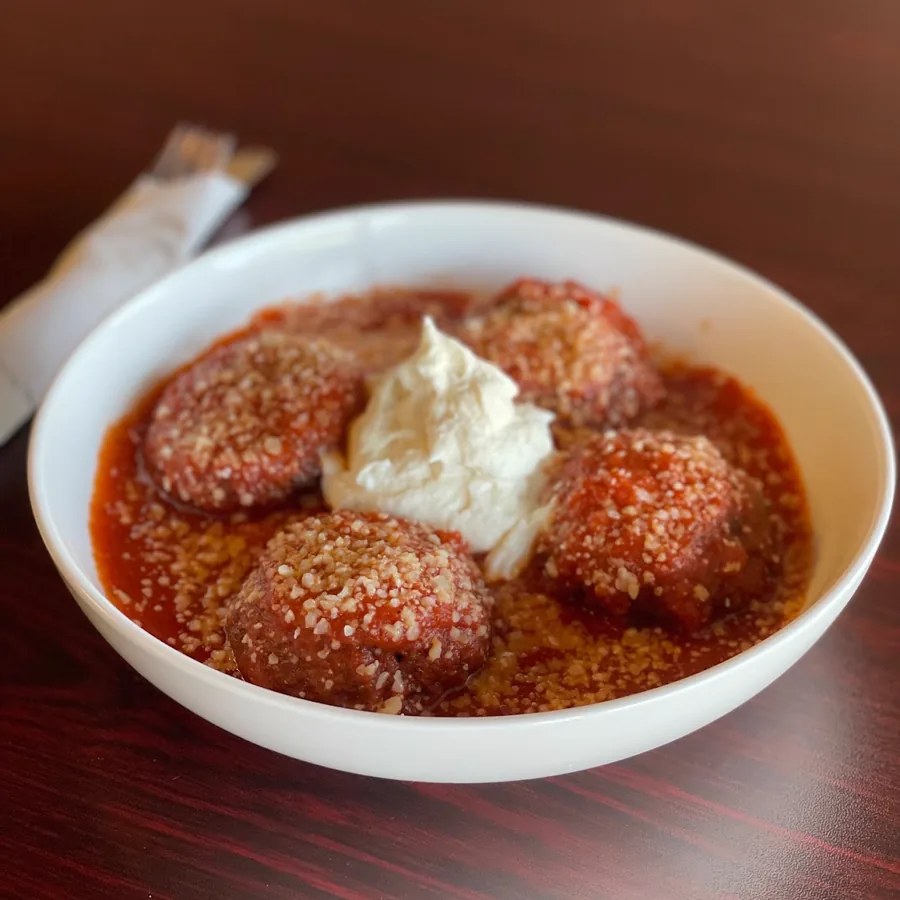 Four house meatballs in marinara topped with parmesan and a scoop of ricotta.