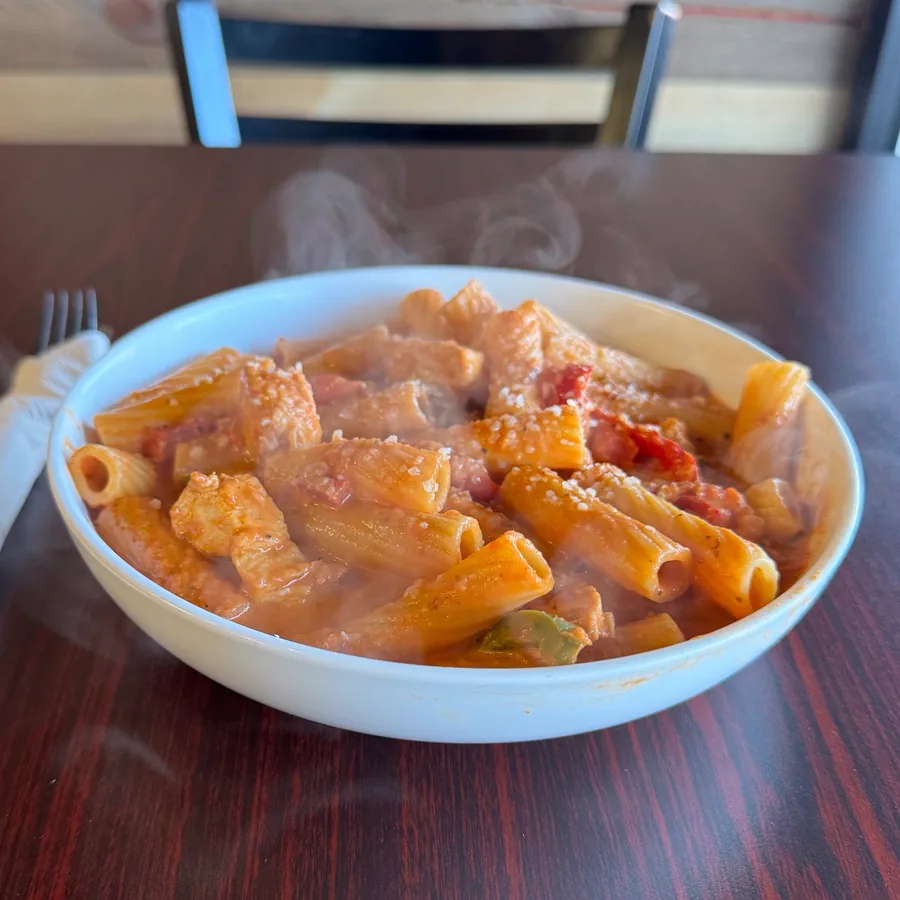 A steaming bowl of chicken riggies — rigatoni in a creamy tomato sauce with peppers and chicken.