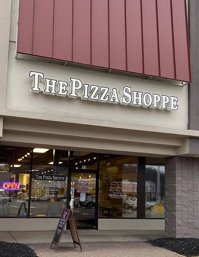 The Pizza Shoppe storefront at Panorama Plaza, with an illuminated sign and an OPEN neon in the window.
